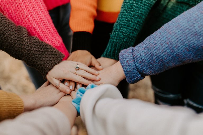 A group of hands it shown piled on top of each other in solidarity.