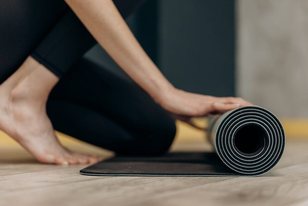 A woman rolls up her yoga mat.