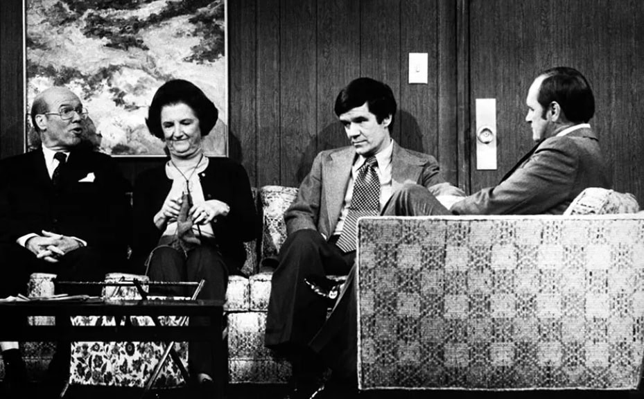 A scene from a TV show that shows several people sitting on a couch looking unhappy.