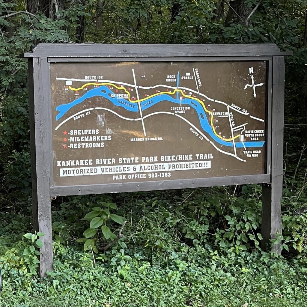 A big wooden sign at the start of a trail has a colorful map.