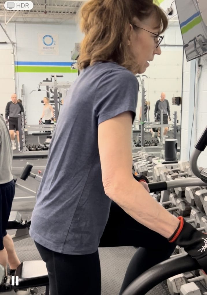 A woman works out in a gym on a stair stepper.