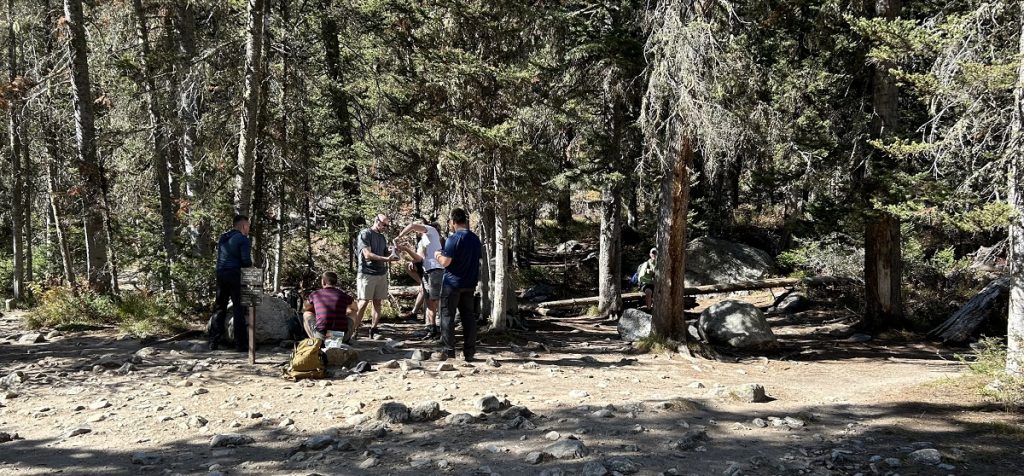 A group of men sit and eat in the shade.