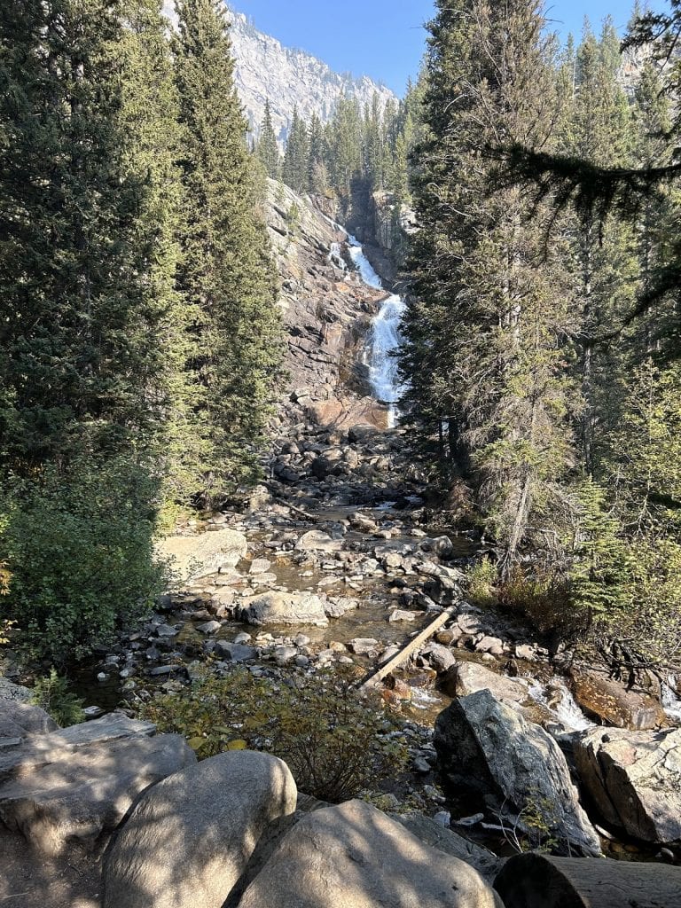 A waterfall looks hidden between tall rocks.