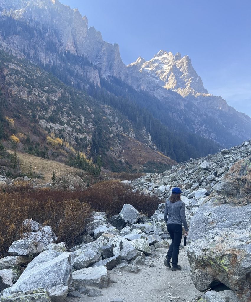 A woman appears to walk slowly surrounded by mountain scenery.