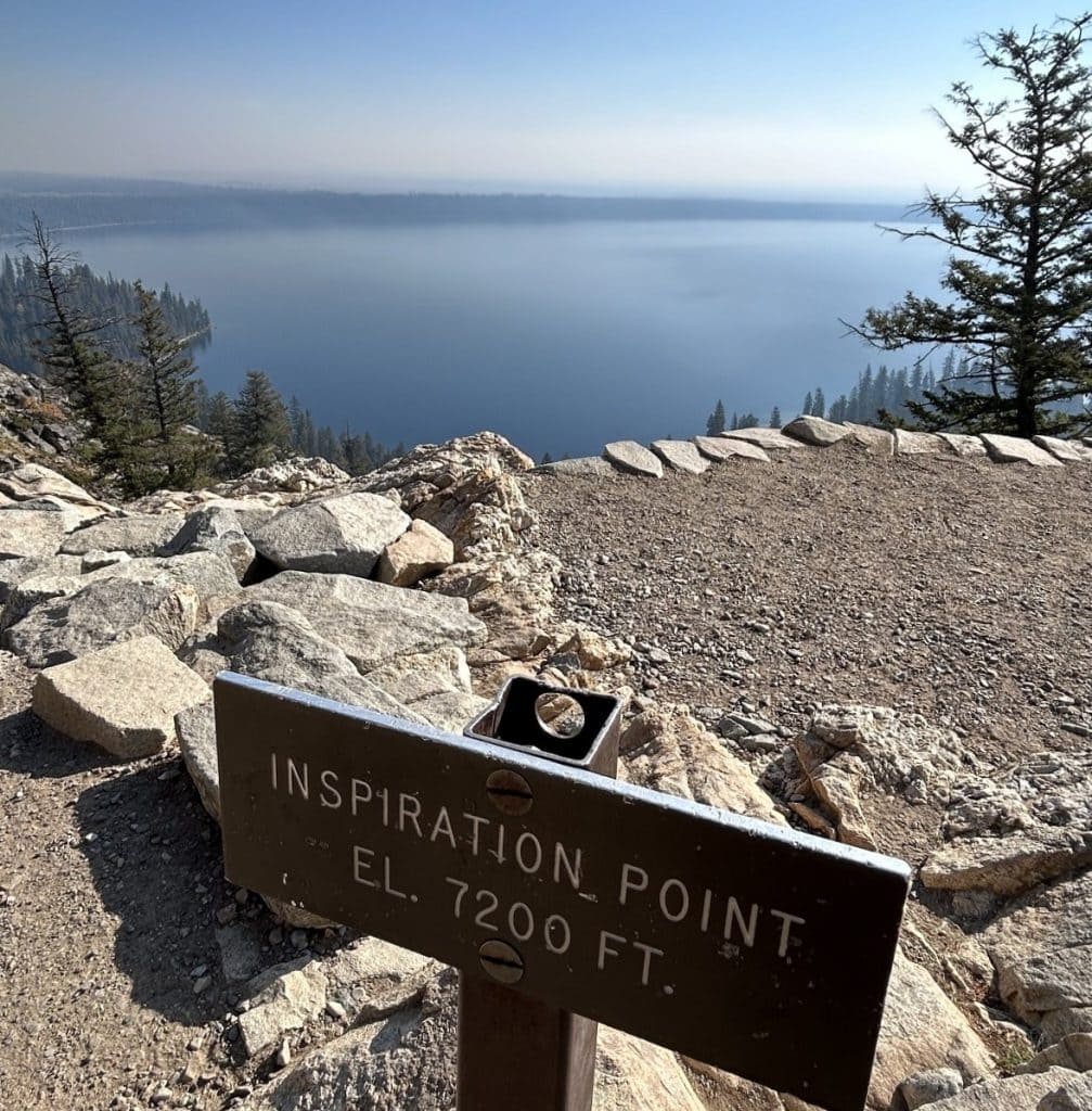  blue lake reflects the sunshine with a bench in the foreground of the lookout.