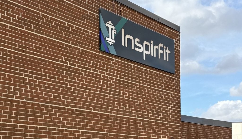 A brown brick building has a sign that says InspirFit on it.
