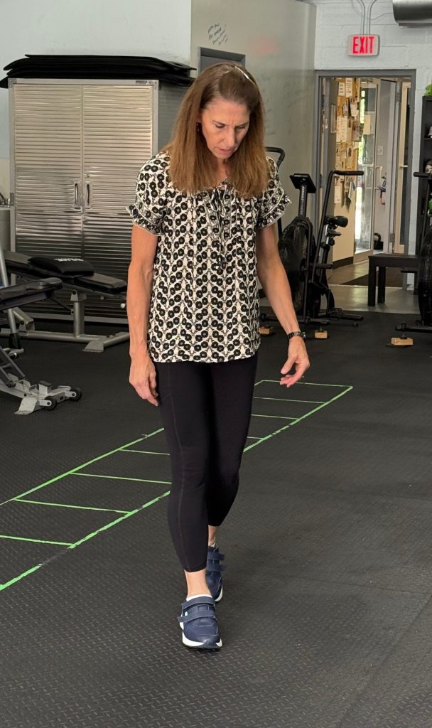 A woman walks slowly with blue shoes on as if she's testing them.
