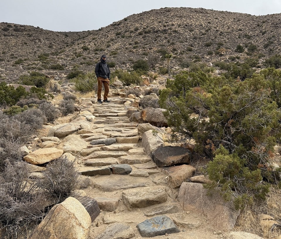 A male hiker continues upward on manmade stairs of rock.