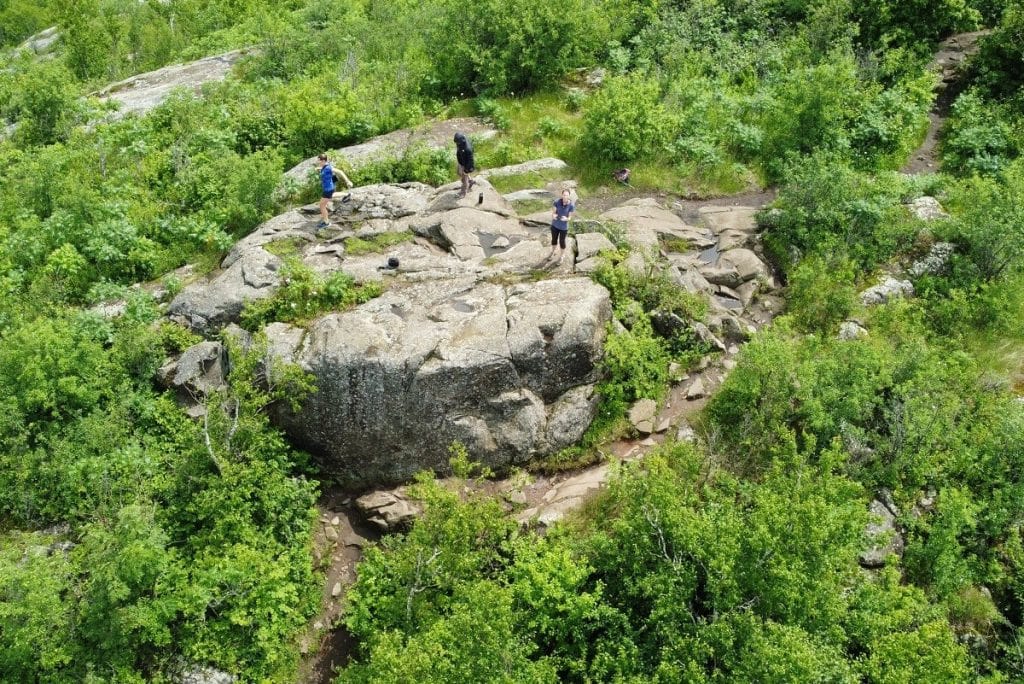 A view from above of a rocky peak with people on it.