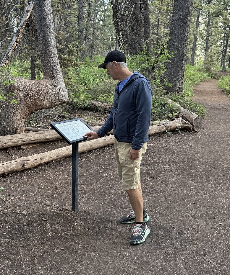 A man reads an interpretive sign along the trail.