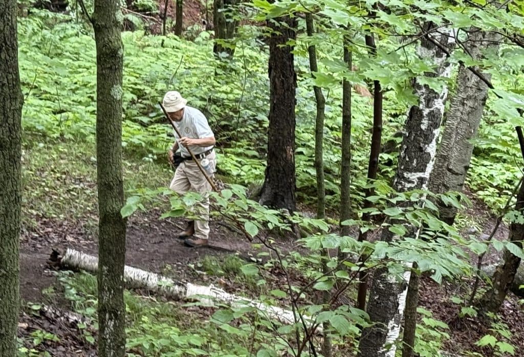 A man walks alone on a path hunched over a bit.