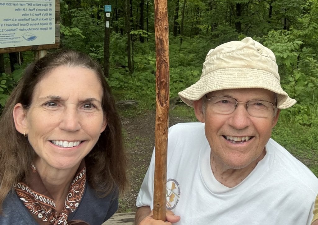A woman poses with an older man wearing a floppy hat.