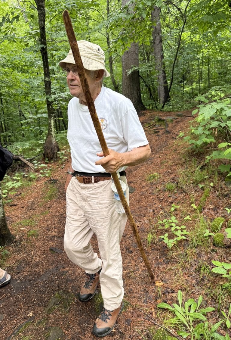 A man walks with a stick slowly.