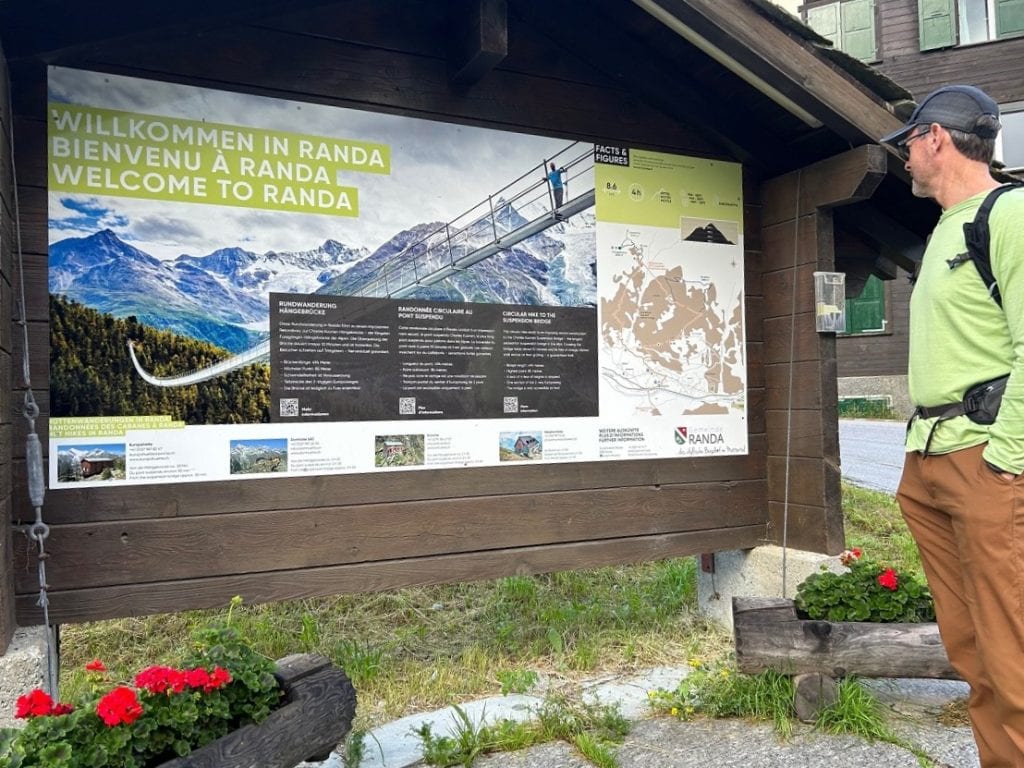 A man looks at an informational sign in a village called Randa.