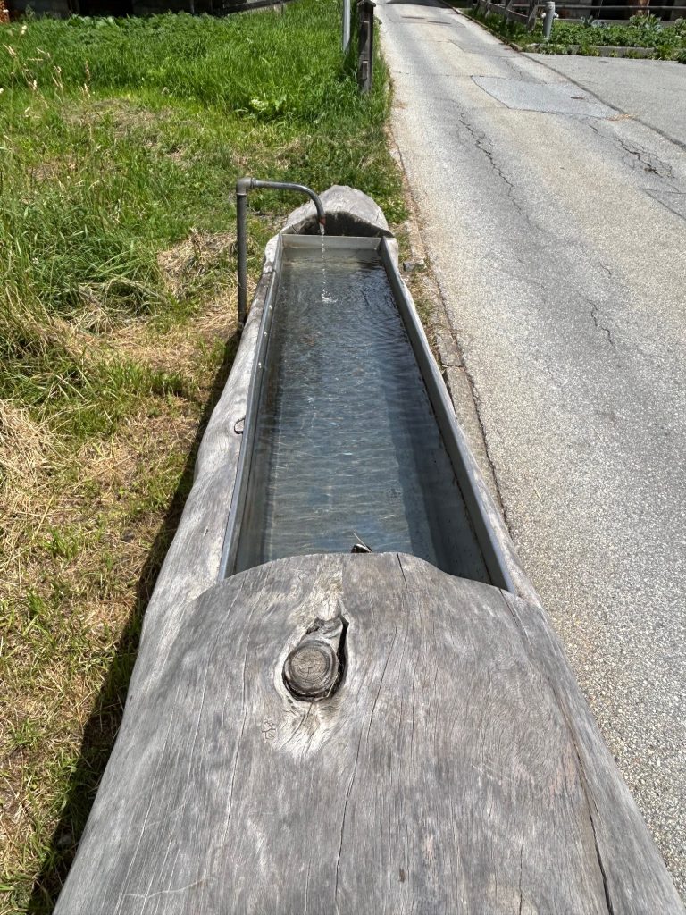 A trough of water is by the side of the road.