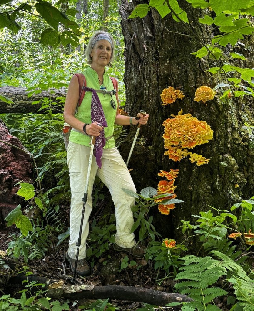 A woman holds hiking poles while posing for a photo.