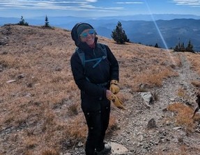 A woman is bundled up to be warm on a hiking path.