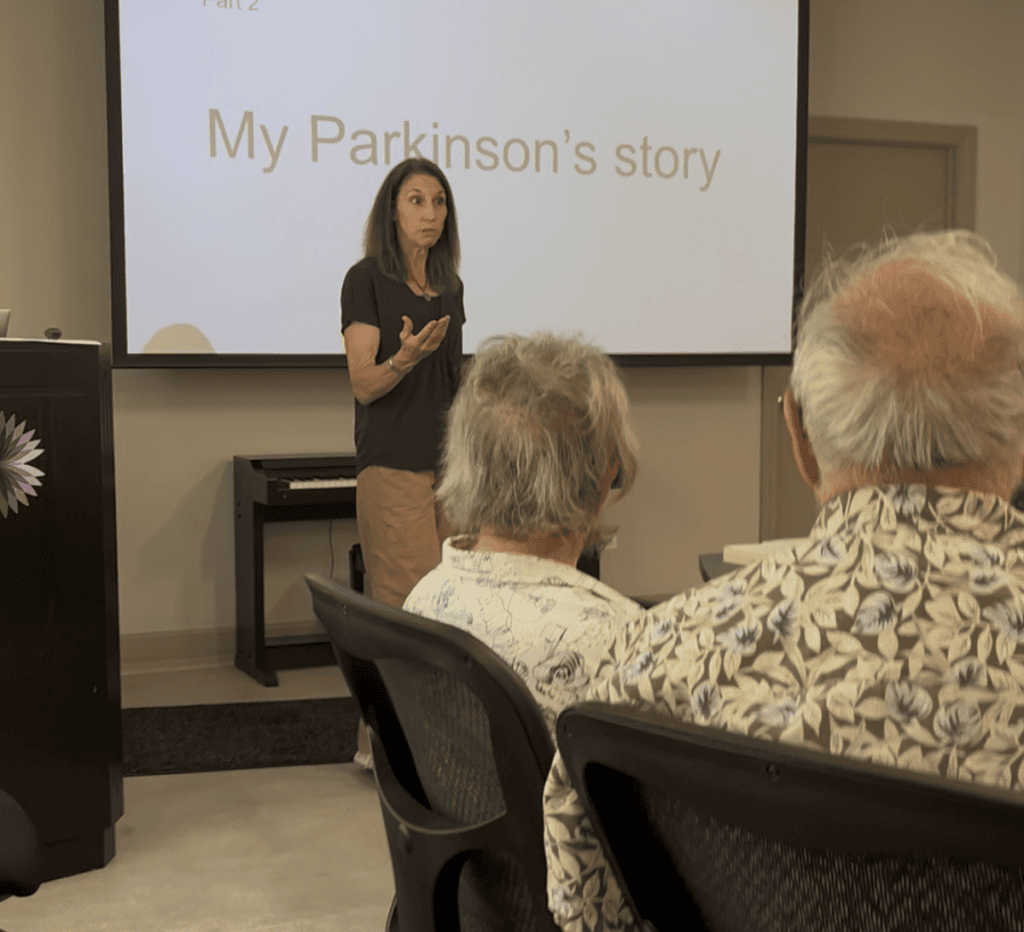A speaker stands in front of a screen that says "My Parkinson's Story."