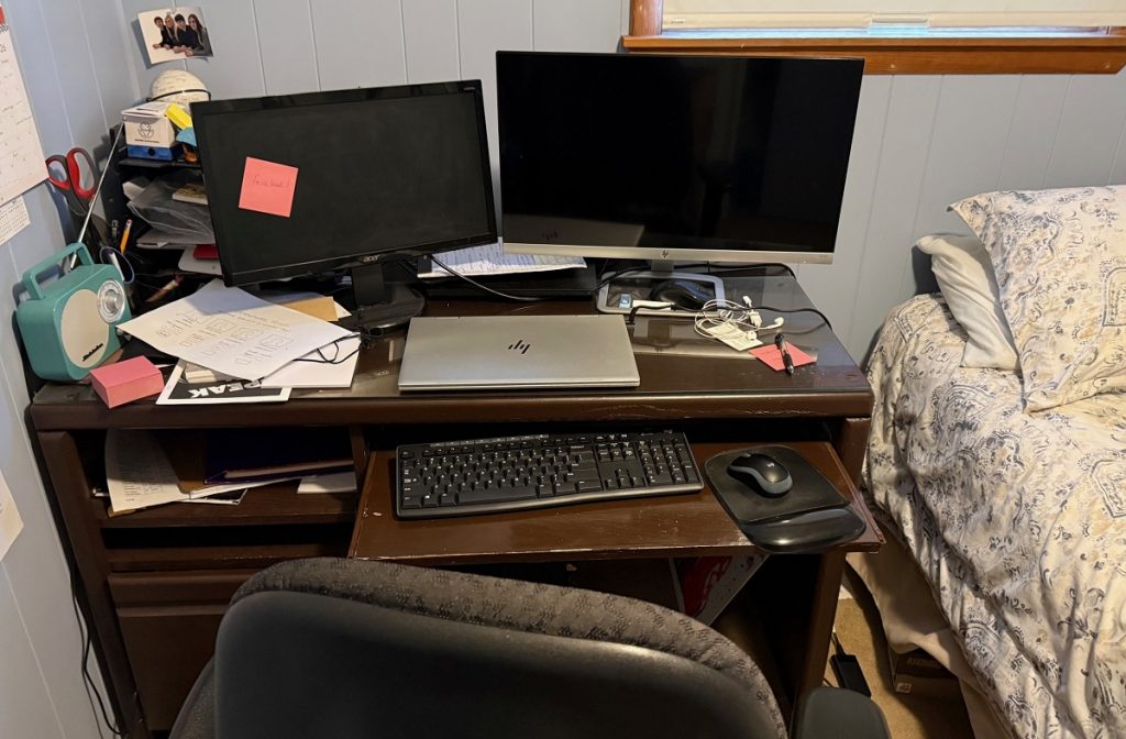 A picture of a messy empty desk with a computer and monitors.