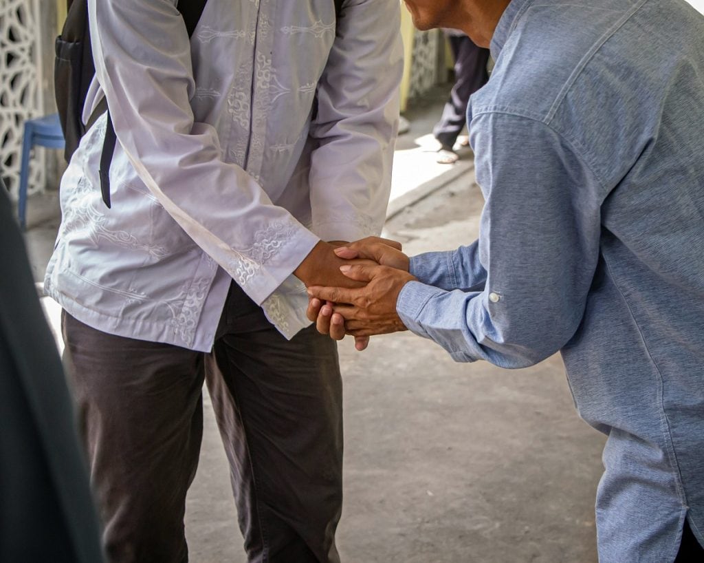 Two people are seen shaking hands in a friendly way.