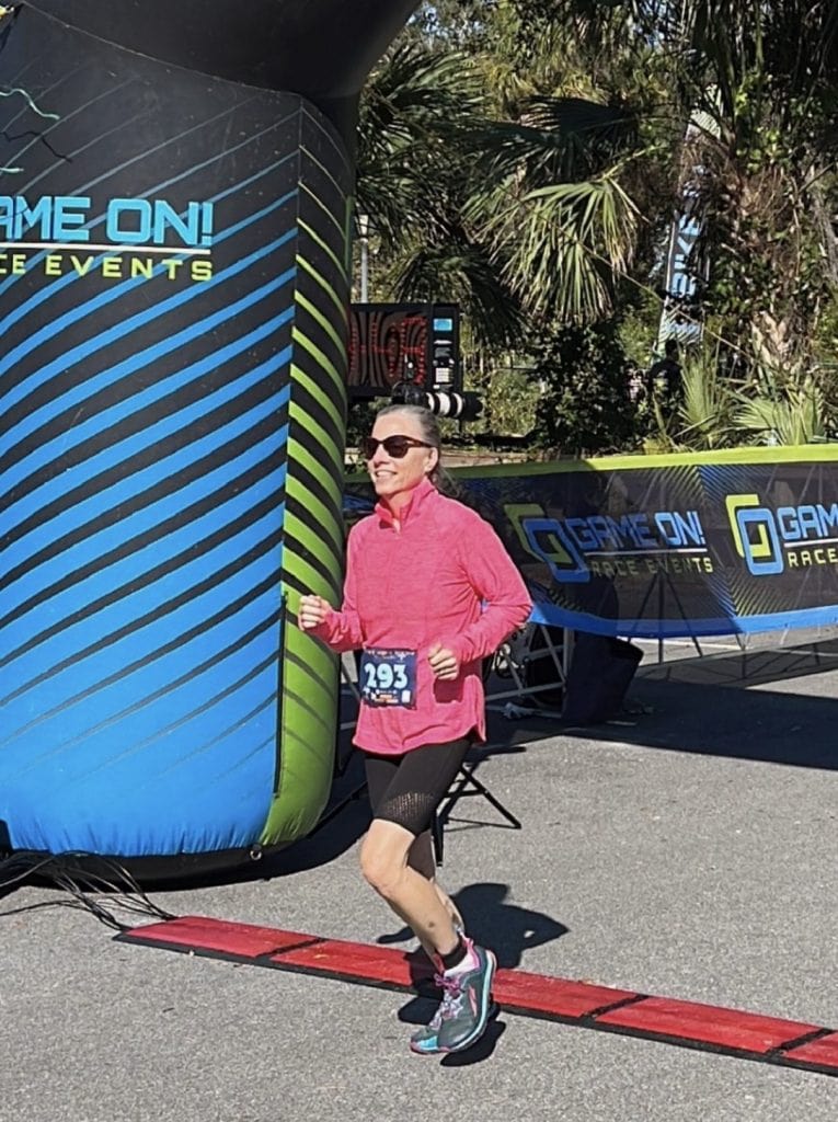 A woman runs through the finish line of a triathlon.