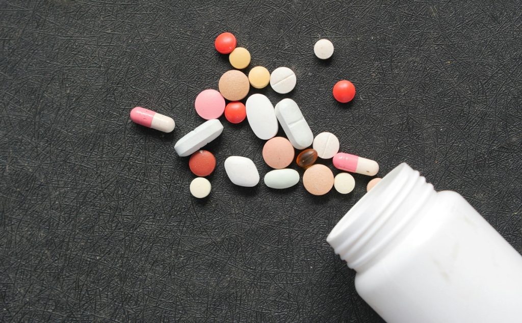 A bunch of colorful pills spill out of a bottle.