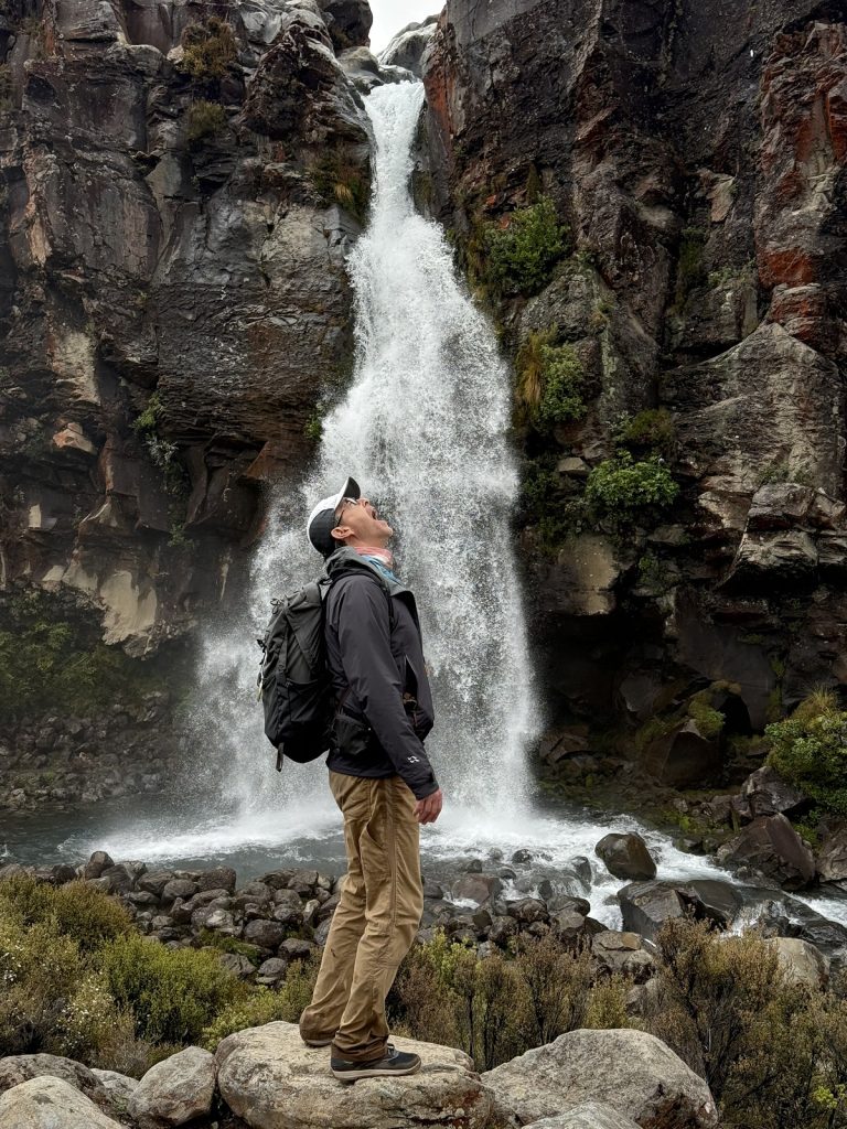 A man tries to drink out of the falls.