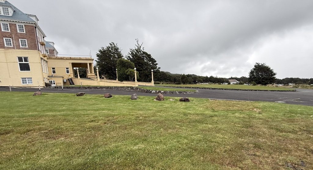 A hotel building is in the distance with a grassy area in the path.