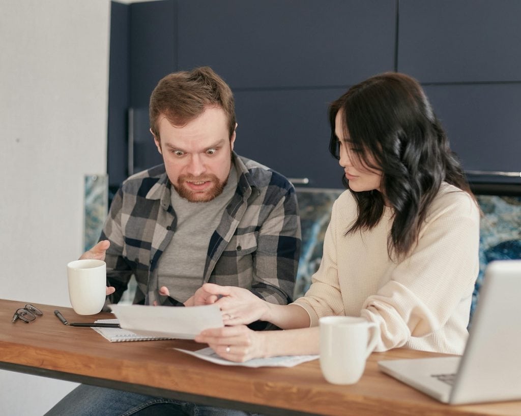Man and woman are looking at papers on a table and are frustrated.