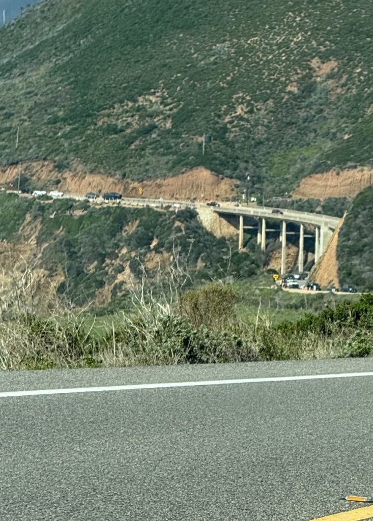 A huge concrete bridge is seen from a car in the distance.