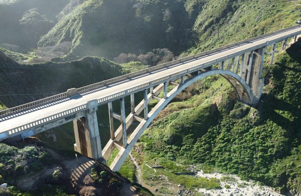A huge, tall concrete bridge spans over a deep valley.