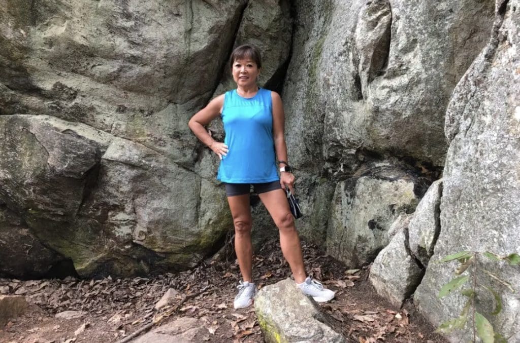 A woman stops in front of a bluff for a hiking picture.