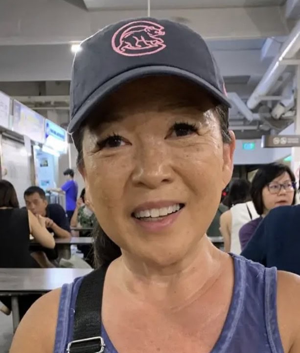 A woman smiles wearing a Cubs hat.