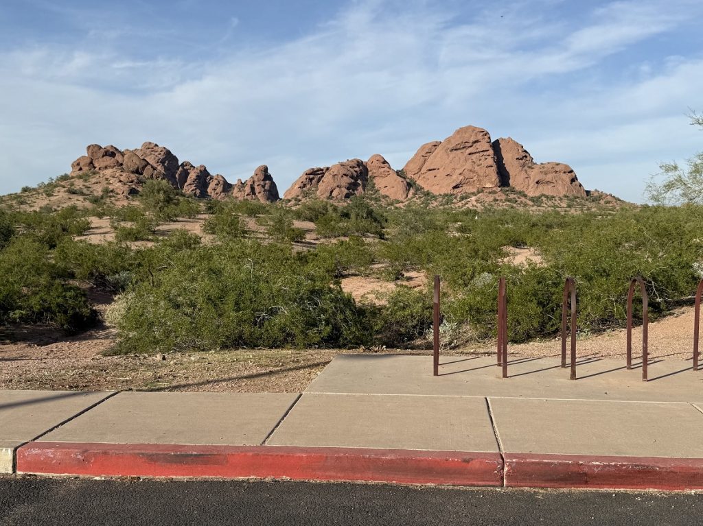 A curb of a parking lot is shown with a butte in the far background.