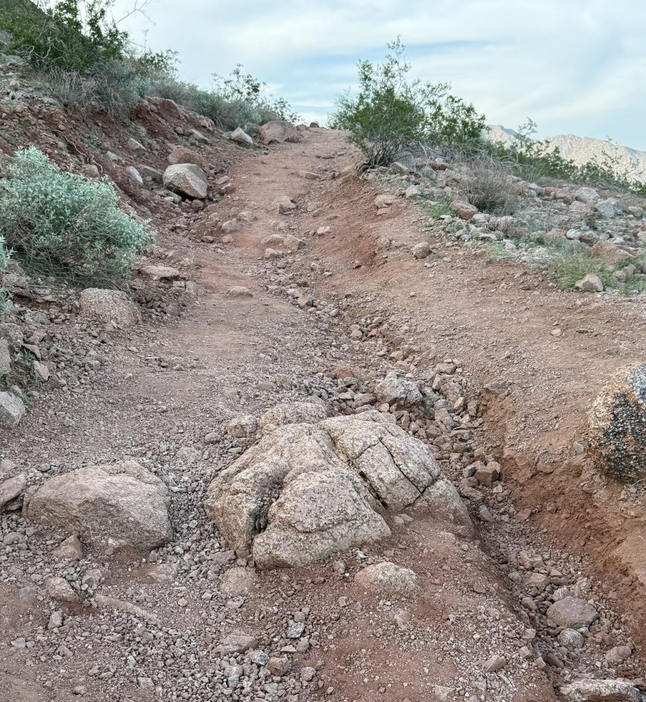 A rocky trail goes up a small hill.