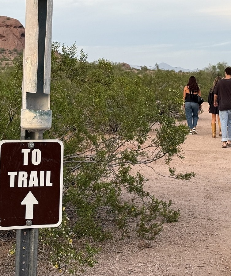 A sign that says "to trail" is next to a group of hikers moving forward.