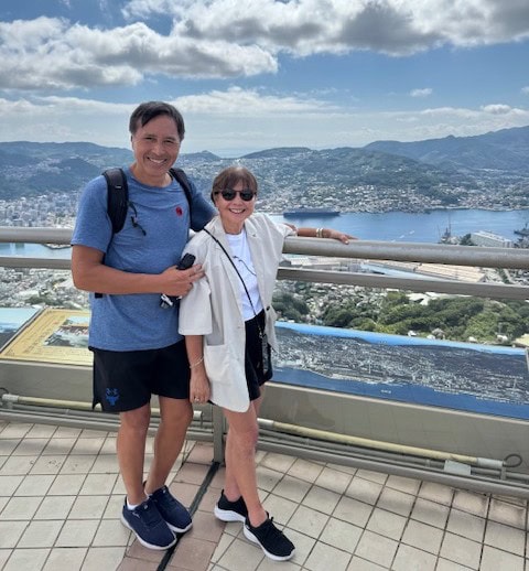 A man and woman stand together on a high platform overlooking a body of water.