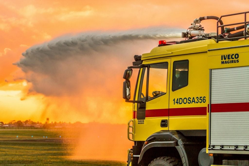 A big yellow truck sprays liquid out onto a field.