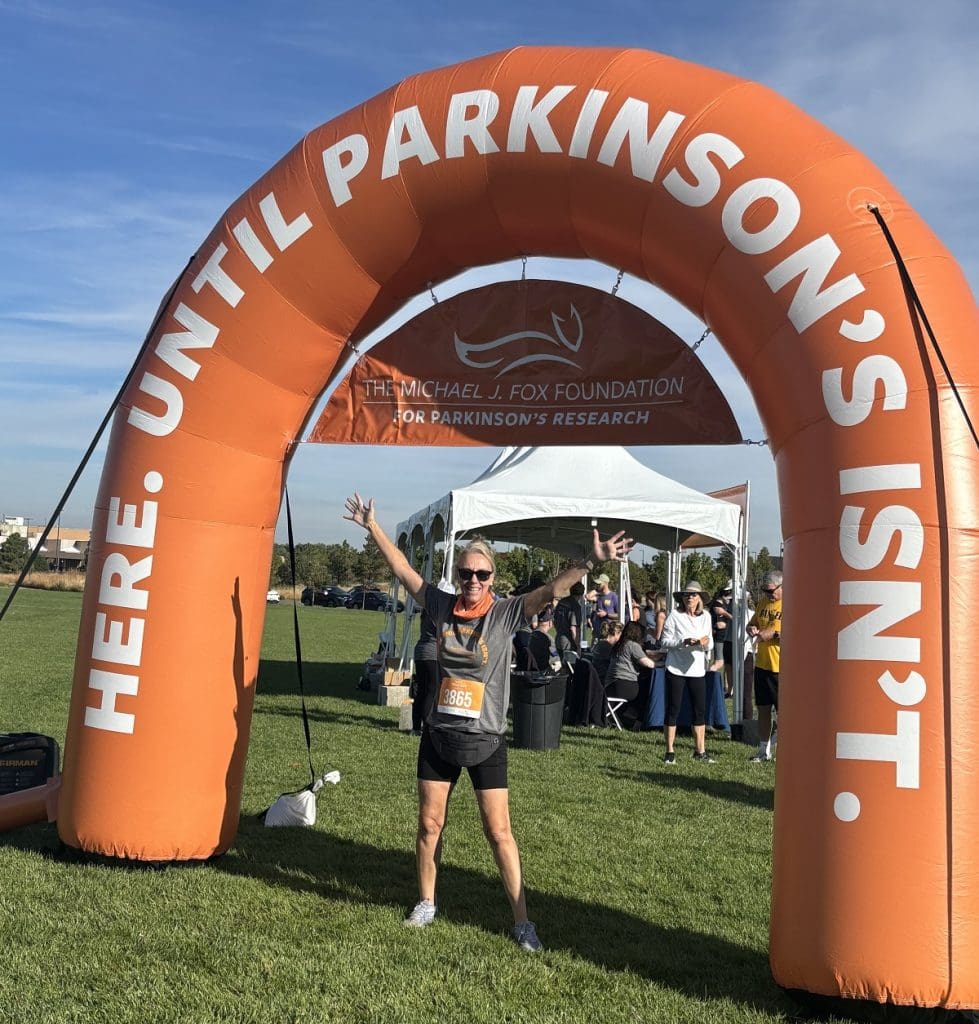 A woman runner runs under a blow-up orange finish marker.