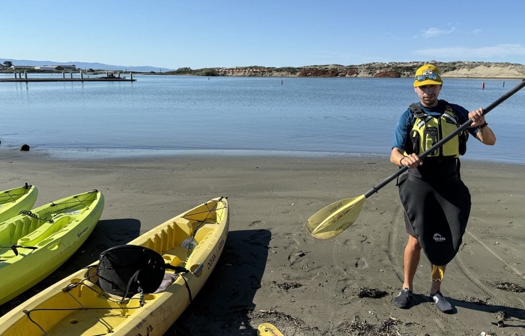 A man demonstrates how to hold a paddle for the kayaks near him.