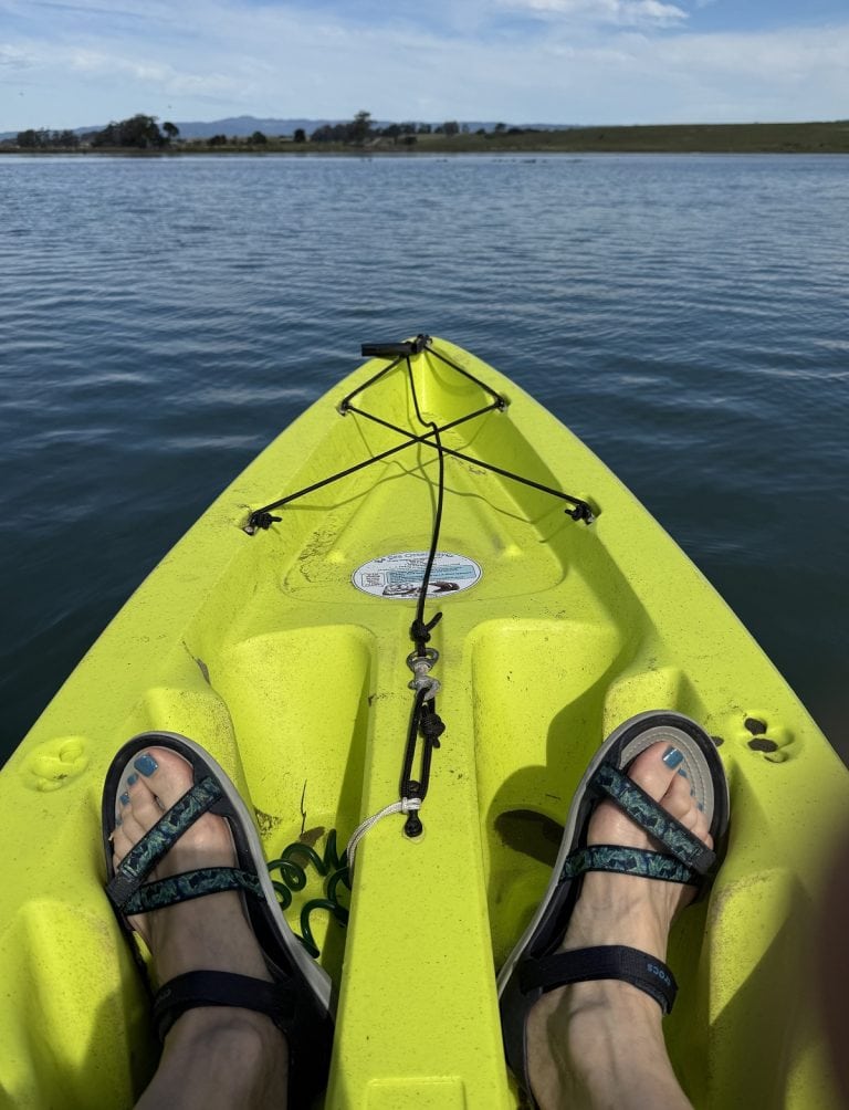 Two feet in sandals are shown in the front part of a boat.