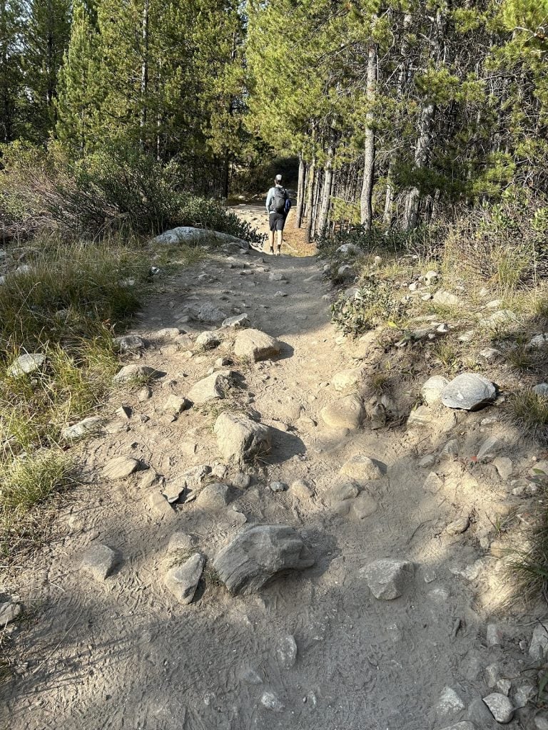 A rocky path is shown with a hiker in the distance.