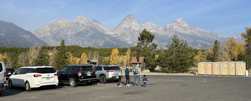 A parking lot with a scenic view of the three big mountains in the Teton Range behind it.