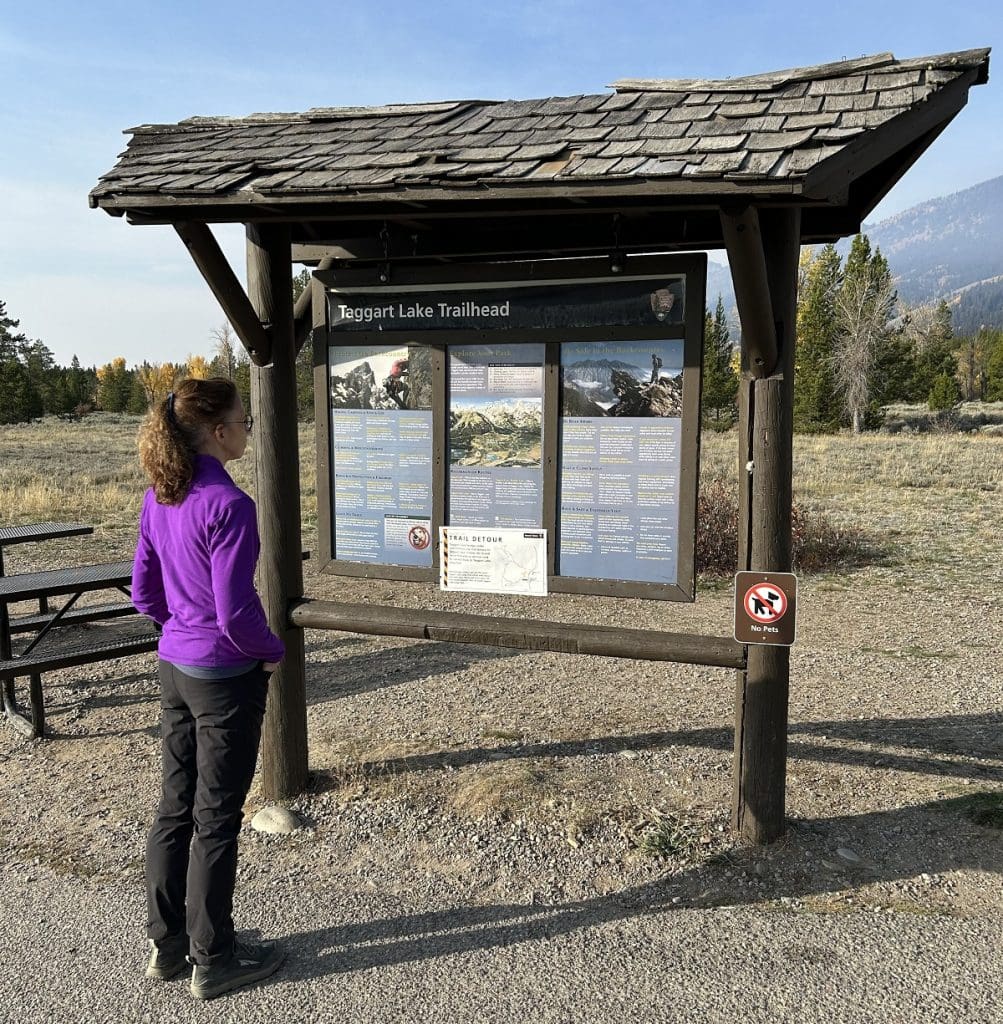 A woman view a map on a kiosk outside.
