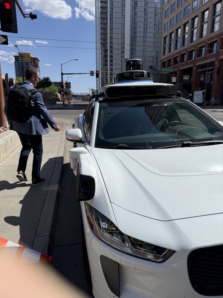 A man gets into a Waymo vehicle.