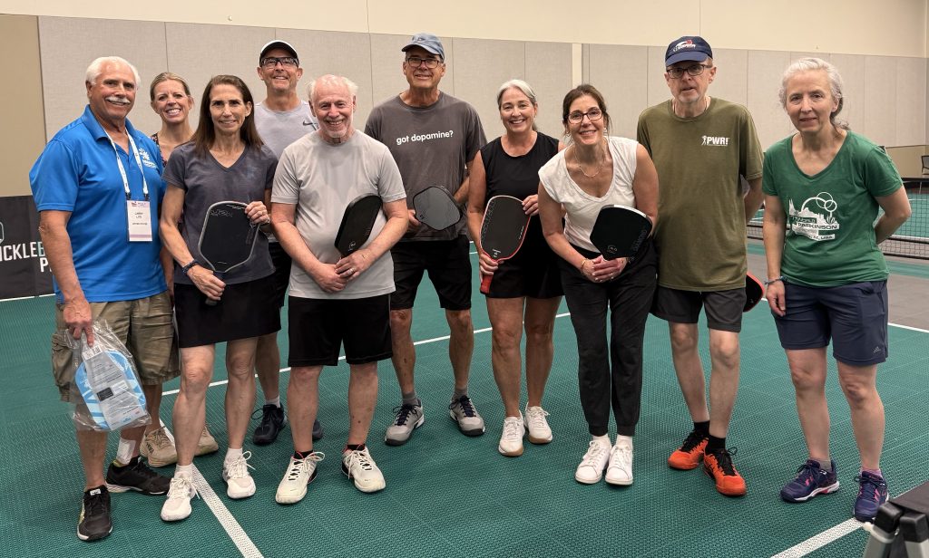 A group of people with pickleball paddles pose for a picture.