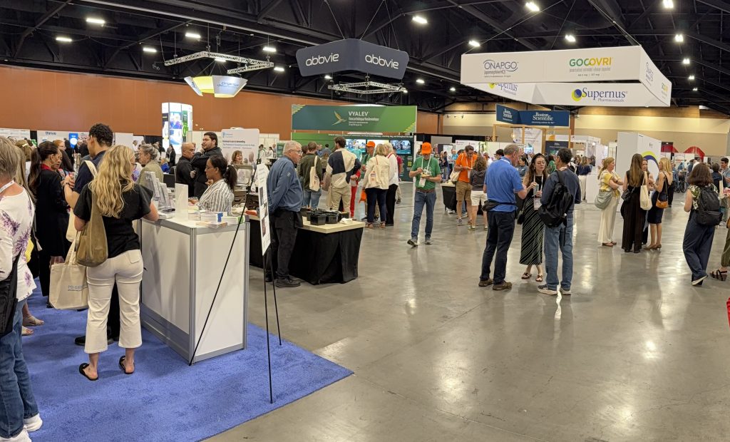 Lots of people look at booths in a spacious room.
