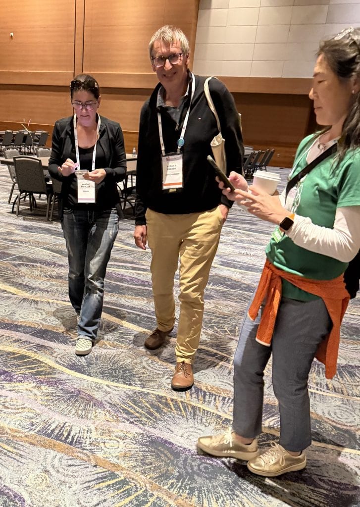 A man walks with two women answering their questions.
