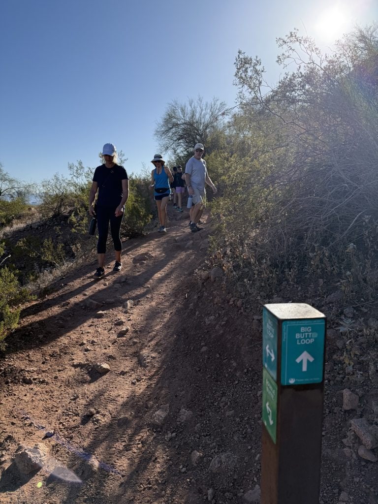 Hikers go around a corner with the sun behind them.