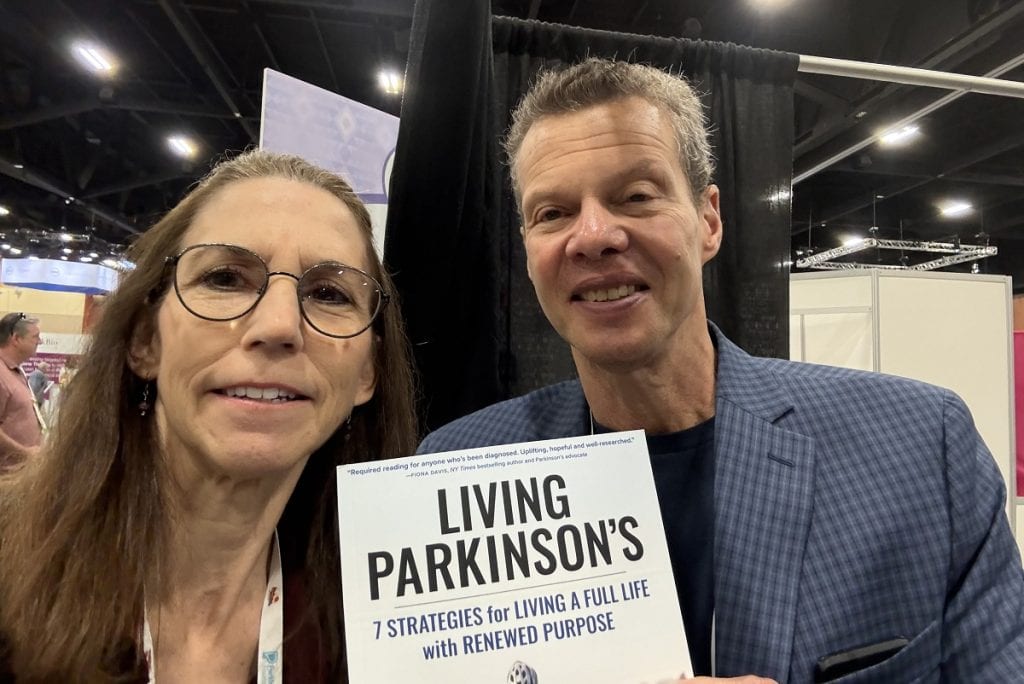 A man and woman smile for the camera while holding a book.
